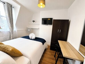 A bedroom with a bed, a desk, a wardrobe, a TV, and a fan. - Double Room in East London near Aldgate East (London)