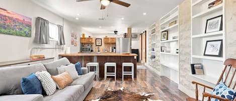 A modern living room with a grey sofa, a cowhide rug, and a wooden chair.