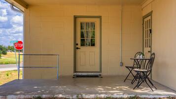 A building entrance with a beige door, a stop sign, and a metal chair outside.