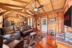 A cozy log cabin interior with a living room, kitchen, and a Netflix sign. - Saw Mill (Lodge #4) Hot Tub & 10 Mins to Main St (Fredericksburg)