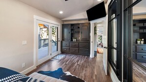 Amplia habitación con ventilador de techo, sistema de entretenimiento integrado y vista al exterior a través de un ventanal corredero.