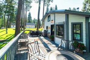 Eine Terrasse mit Sitzgelegenheiten, einem Grill und einem kleinen Gebäude mit Fenster.