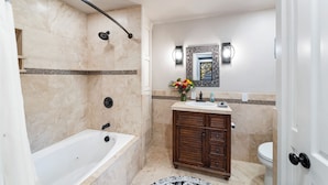 Un baño con bañera, ducha, tocador con lavabo e inodoro.