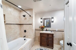 Ein Badezimmer mit einer Badewanne, einer Dusche, einem Waschtisch und einer Toilette.