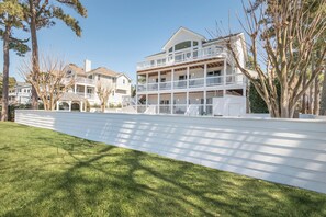 Un immeuble résidentiel à plusieurs étages, à l’extérieur blanc, doté de nombreux balcons et d’une pelouse bien entretenue.