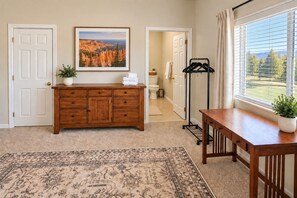 A room with a wooden dresser, a rug, a framed landscape photo, and a window with a view.