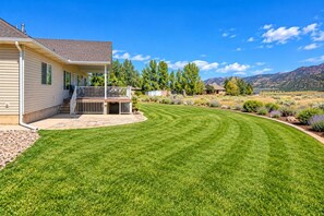 A residential property with a well-maintained lawn, a covered porch, and a view of mountains in the background.