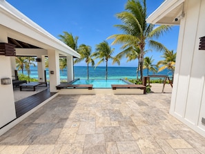 A pool area with a view of the ocean, palm trees, and a covered seating area. - Camp Bay Beach House – Private Pool and Beachfront (Camp Bay)