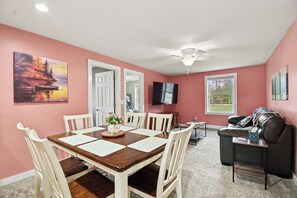 A dining area with a wooden table and chairs, a ceiling fan, and a TV mounted on the wall. - Lakefront Retreat - Gladwin (Gladwin)