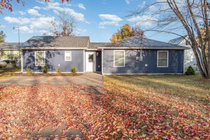 A two-story house with a garage, a driveway, and a lawn covered with fallen leaves. - Lakefront Retreat - Gladwin (Gladwin)