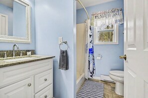 A bathroom with a sink, mirror, towel ring, shower curtain, toilet, and a door. - Lakefront Retreat - Gladwin (Gladwin)