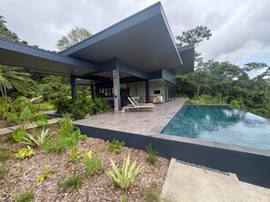 Ein modernes Haus mit Swimmingpool, umgeben von üppiger Bepflanzung.