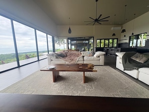 A spacious living room with a large window, a wooden coffee table, and a white sofa. - NEW OASIS! Excellent panoramic views, private pool brand new. (Savegre)