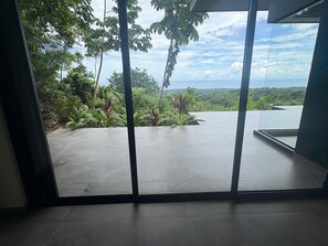 Ein modernes Interieur mit großen Glasüren, die auf einen Balkon mit Blick auf eine üppige Landschaft führen.