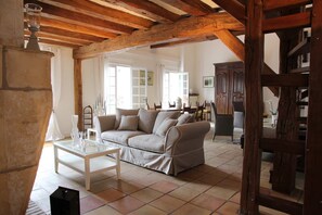 A cozy living room with a wooden ceiling, a sofa set, a glass coffee table, and a dining area in the background. - Maison de Charme 10p - Montrésor (Montrésor)