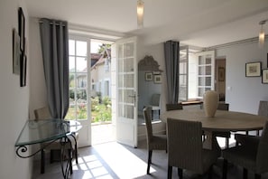 A dining area with a round table, chairs, and a glass-top table. - Maison de Charme 10p - Montrésor (Montrésor)
