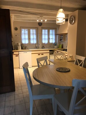 Una cucina con un tavolo da pranzo e sedie, un lampadario e una finestra con persiane.