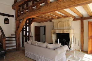 A room with a wooden ceiling, a fireplace, a sofa, and a staircase. - Maison de Charme 10p - Montrésor (Montrésor)