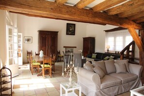 Ein geräumiger Wohnbereich mit Holzboden, einem Esstisch mit Stühlen, einer Couch und einem Schrank.