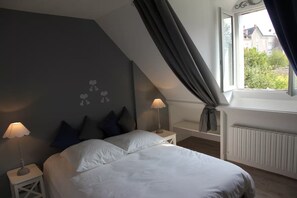 A bedroom with a bed, two bedside tables, a window with curtains, and a radiator. - Maison de Charme 6p - Montrésor (Montrésor)