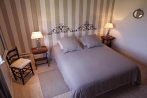 Ein Schlafzimmer mit einem Bett, zwei Nachttischen inklusive Lampen, einem Sessel und einer Heizung.