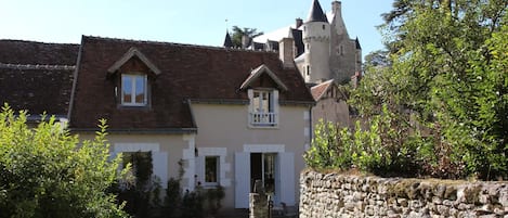 A traditional stone building with a pitched roof, a small attached structure with a gabled roof, and a stone wall with a gate.