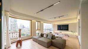 A modern living room with a sectional sofa, a flat-screen TV, and a giraffe decoration.