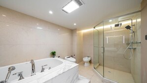Et moderne badeværelse med et stort badekar, en glasafskærmet brusekabine og et toilet.