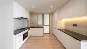 A modern kitchen with white cabinetry, a black countertop, and recessed ceiling lights.