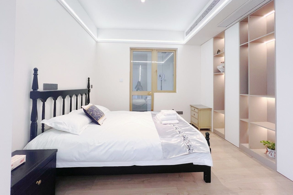 Quarto com cama, mesas de cabeceira, guarda-roupa e espelho.