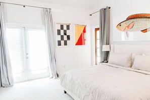 Ein Schlafzimmer mit Bett, Vorhängen, einem Fenster und Bildern an der Wand.