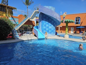 Una piscina con un tobogán azul y una palmera.