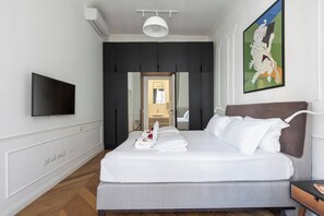 Ett hotellrum med en säng, en tv, en tavla och en garderob.