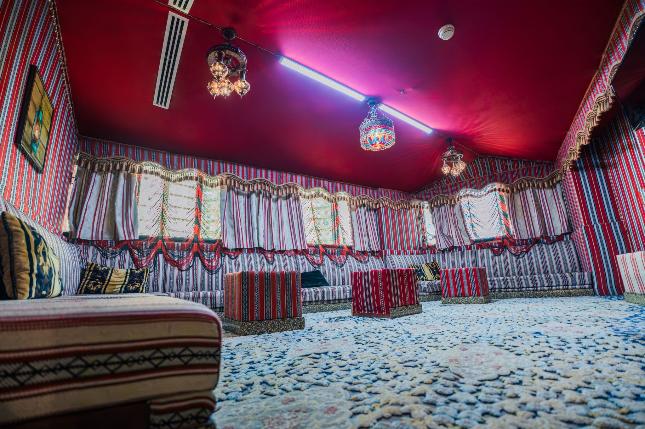 Une pièce avec des rideaux à rayures, une moquette à motifs et un plafond rouge.