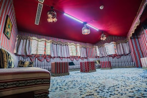 Una habitación con cortinas a rayas, alfombra estampada y techo rojo.