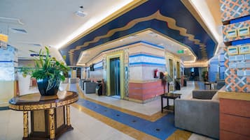 Um hall de entrada com balcão de recepção, área de estar e teto decorativo.