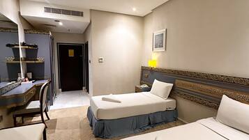 A hotel room with two beds, a desk, a chair, and a mirror.