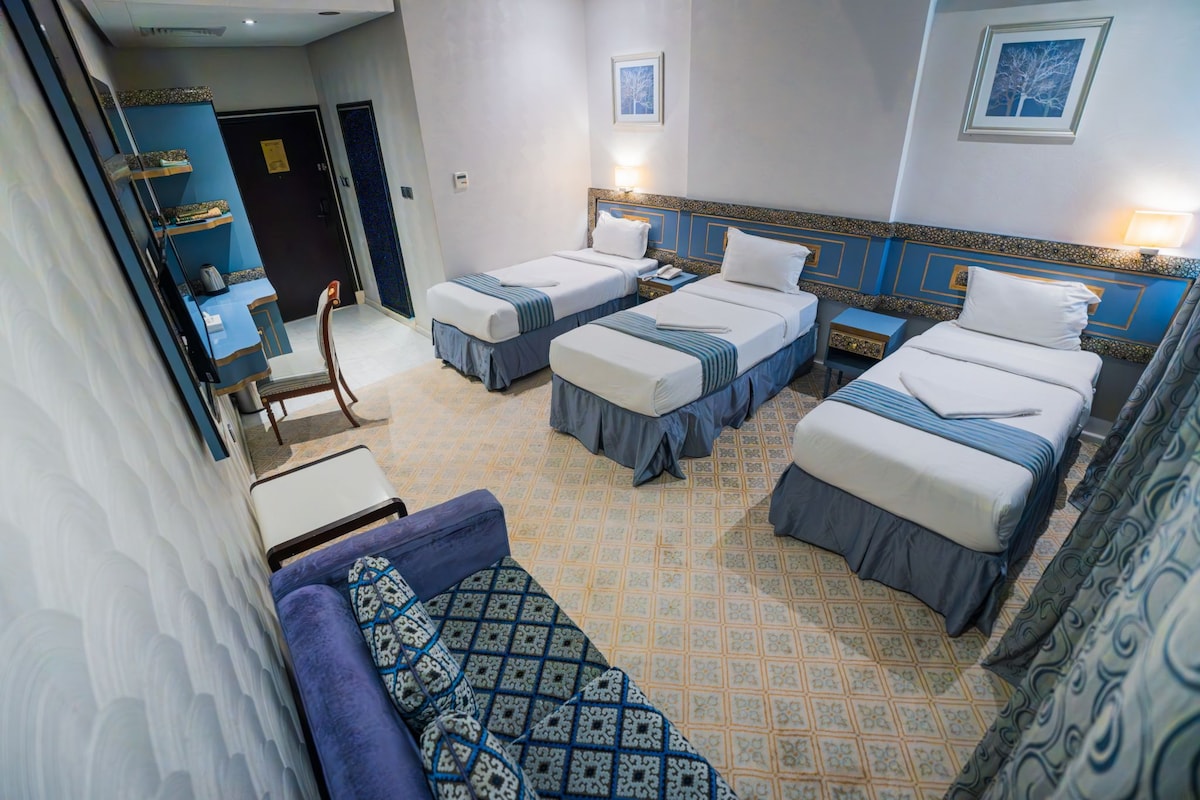 Una habitació d'hotel amb dos llits individuals, un sofà i una taula petita.