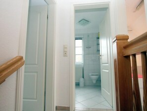 A narrow hallway leading to a bathroom with a toilet, a shower, and a window. - Waldstrasse 6c, Holiday Home Halligflieder (Wyk auf Foehr)
