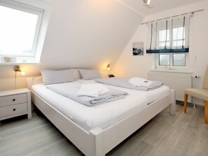 A bedroom with a single bed, bedside tables, a chair, and a window with curtains. - Waldstrasse 6c, Holiday Home Halligflieder (Wyk auf Foehr)