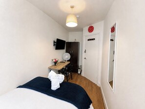 A bedroom with a bed, a desk with a chair, a fan, and a wardrobe. - Compact Double Room near Aldgate East, London (London)