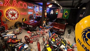A garage with various vehicles, including cars and motorcycles, and a Texaco sign. - Olla Hotel  (Montes Claros)