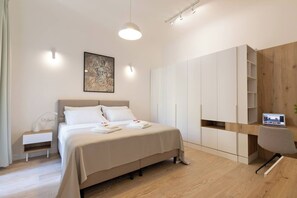 Una camera d'albergo moderna con un letto, un comodino, una scrivania e un armadio.