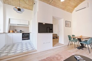 A modern kitchen with white cabinets, a built-in oven, and a dining area with teal chairs and a wooden table. - Charming 1BR Apartment with Balcony near Vatican — Prati, Rome (Rome)