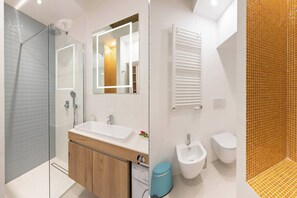 Un bagno moderno con box doccia in vetro, un lavabo con specchio, un bidet e un water.