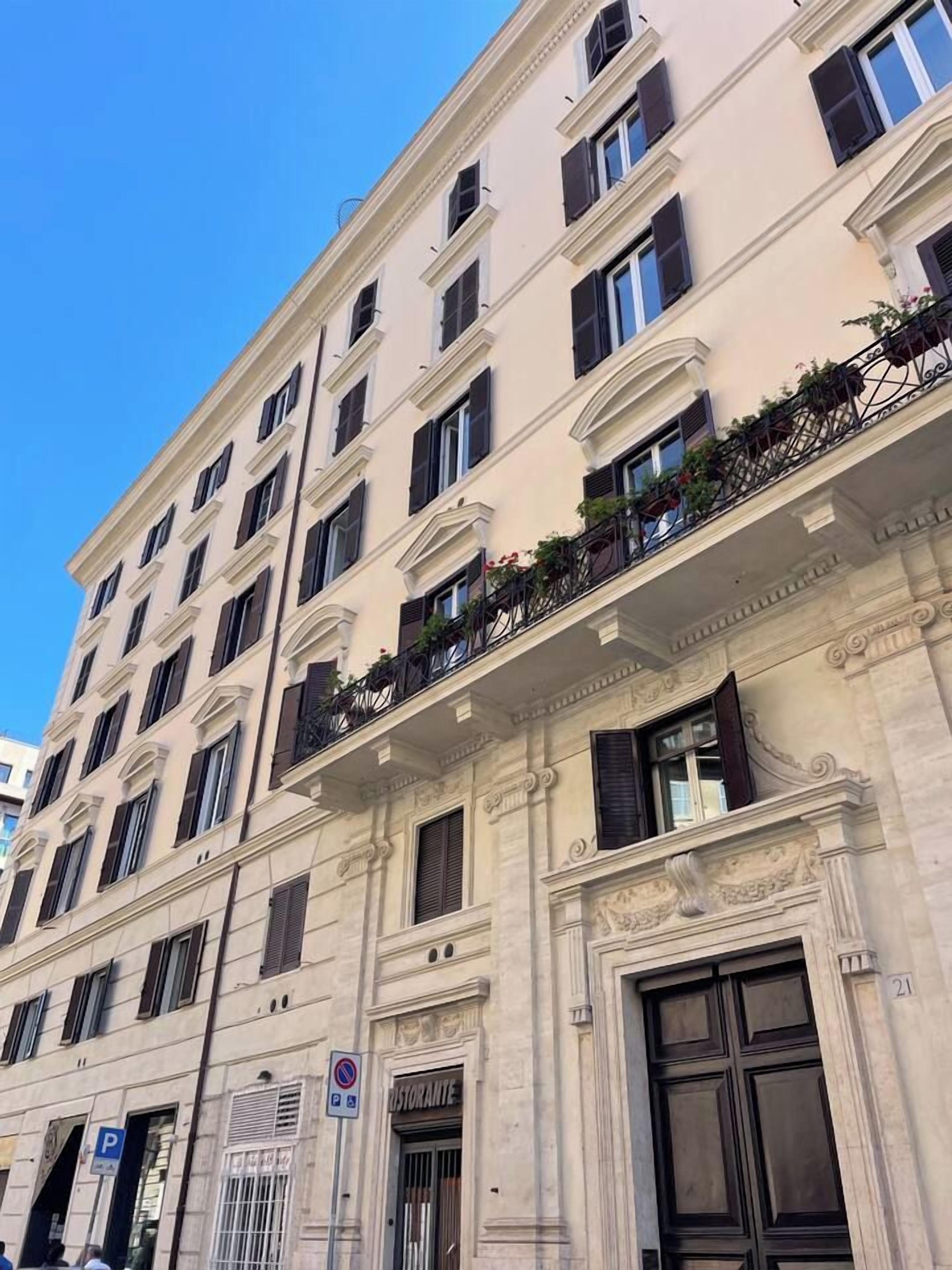 A multi-story building with a classic architectural style, featuring a balcony with plants and a door labeled 'Ristorante' indicating a restaurant on the ground floor.
