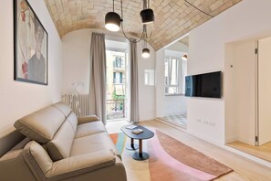 A modern living room with a sofa, a small table, and a TV mounted on the wall. - Charming 1BR Apartment with Balcony near Vatican — Prati, Rome (Rome)