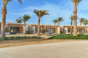 Ein modernes Resort mit mehreren Villen, Palmen und blauem Himmel.