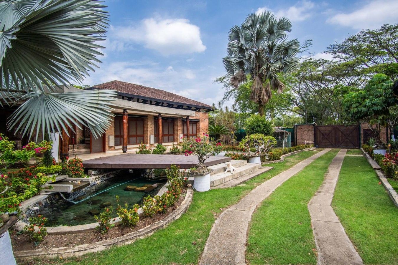 A residential property with a swimming pool, a covered patio, and a well-maintained garden.