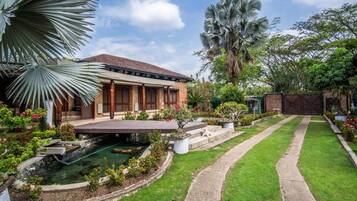 A residential property with a swimming pool, a covered patio, and a well-maintained garden.